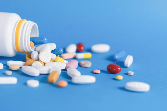 multiple pills displayed alongside bottle on a blue background